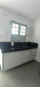 een keuken met witte kasten en een zwart aanrechtblad bij RC FLAT Studio 05 Tamandaré, à 200m da praia in Tamandaré