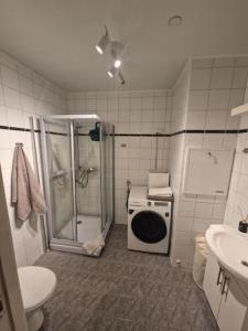 a bathroom with a shower and a washing machine at Leilighet i Tromsø in Tromsø