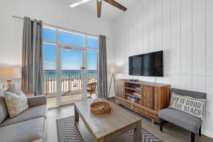 a living room with a tv and a couch and a table at Windemere 301 in Perdido Key