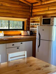a kitchen with a white refrigerator and a table at Cabañas Laguna de los Sauces in Azul
