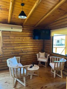 a room with chairs and a table and a tv at Cabañas Laguna de los Sauces in Azul