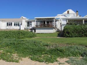a large white house with a porch and a yard at Point Village Accommodation - Hemel op Aarde in Mossel Bay