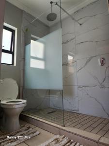 a bathroom with a glass shower with a toilet at Oblique Boutique House in Centurion