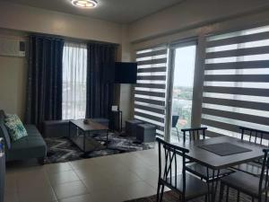 a living room with a table and chairs and a room with a view at Cozy, spacious and well lighted condo in Iloilo City
