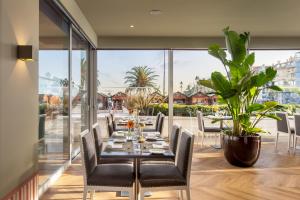 a dining room with a table and chairs and a large window at Hotel Baia in Cascais