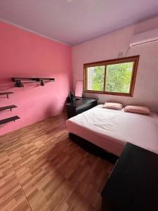 a bedroom with pink walls and a bed and a window at Casa na beira do rio com Lareira in Itati