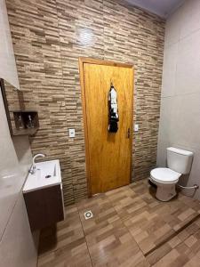 a bathroom with a toilet and a wooden door at Casa na beira do rio com Lareira in Itati +22 photos