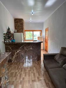 a living room with a couch and a kitchen with a christmas tree at Casa na beira do rio com Lareira in Itati