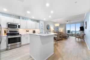 a kitchen with white cabinets and a living room at Spanish Key 105 in Perdido Key
