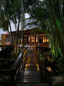 een houten loopbrug die naar een restaurant met palmbomen leidt bij Morada da Xica in Guarda do Embaú