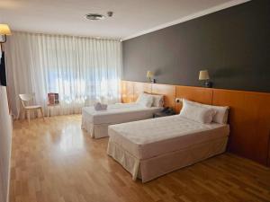 a hotel room with two beds and a large window at AP Hotel Madrid Airport in Madrid