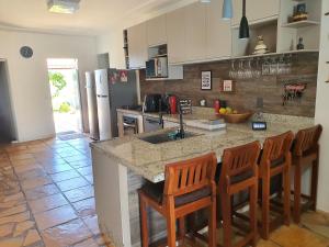 eine Küche mit einer Theke mit einer Spüle und einigen Stühlen in der Unterkunft Casa Colorida em Touros in Touros