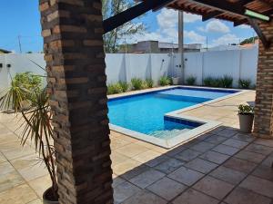 einen Pool im Hinterhof mit einer Backsteinsäule in der Unterkunft Casa Colorida em Touros in Touros