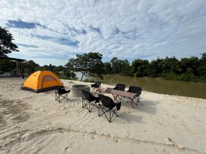 Una mesa y sillas y una carpa en la playa. en Riverland Camp, en Phumĭ Chheutéal (2) 24 fotos más