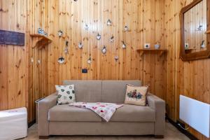 a couch in a room with a wooden wall at Sendy Home Roccaraso 1 in Roccaraso