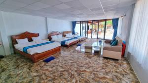 a hotel room with two beds and a couch and chairs at Vung Bau Resort in Phú Quốc