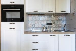 a kitchen with white cabinets and a sink at Sendy Home Roccaraso 3 in Roccaraso