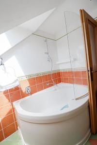 a bathroom with a white tub and orange tiles at Apartman Anton Kvačany in Kvačany