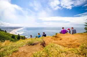a group of people sitting on a hill overlooking the ocean at Neptunes Grand View in Lincoln City