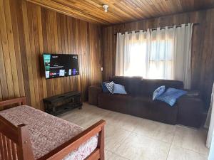 a living room with a couch and a flat screen tv at Casa Brisa Leve in Balneário Gaivotas