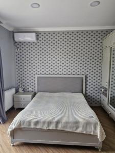 a bedroom with a bed and a patterned wall at Jumber&Lela in Batumi