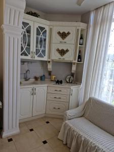 a kitchen with white cabinets and a couch in a room at Jumber&Lela in Batumi
