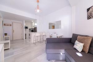 a living room with a gray couch and a kitchen at 1st line Paseo marítimo en el puerto deportivo de Marbella in Marbella