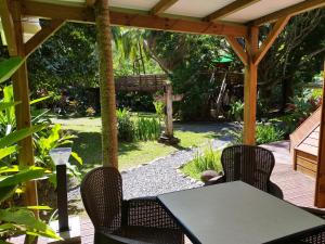 a patio with a table and chairs under a pergola at Gite du Manial Tipi bois Danse du Soleil in Pointe-Noire