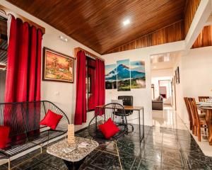 a living room with red curtains and a table and chairs at Gaby's Home In Downtown La Fortuna in Fortuna