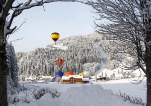 dos globos de aire caliente volando sobre un pequeño pueblo en la nieve en Gästehaus Herrmann, en Filzmoos