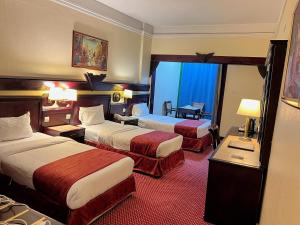 una habitación de hotel con dos camas y un escritorio en Claridge Hotel, en Dubái 95 fotos más