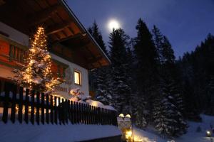 un arbre de Noël devant une maison dans la neige dans l'établissement Gästehaus Herrmann, à Filzmoos