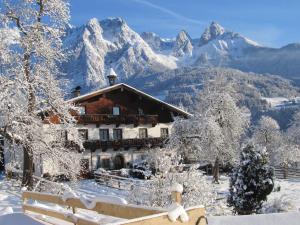 a building with snow covered mountains in the background at Bio-Bauernhof Rettenbachgut in Werfen