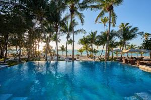 a swimming pool next to a beach with palm trees at Tiamo Resort in Congo Town