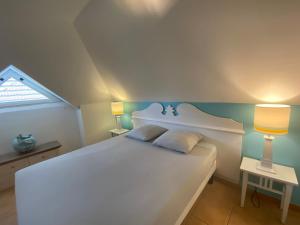 una camera da letto con un grande letto bianco con due lampade di Appartement, 2 chambres, Terrasse vue mer, très calme, Piscine premium, accès direct aux plages, restaurants, Village Vacances a Sainte-Luce