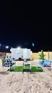 a beach with chairs and a table and a trailer at Big bear camping in Nafīr