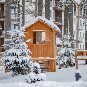 una cabaña de madera en la nieve con un árbol en Diamond grey Titova Vila, en Zlatibor