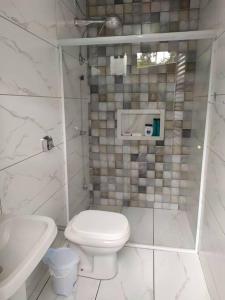 a white bathroom with a toilet and a sink at Casa com Piscina e ampla area de festas in Barra Velha +16 photos