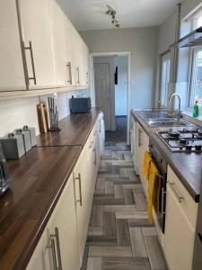 a kitchen with white cabinets and a wooden floor at Stylish 3-Bedroom House in Warrington - Sleeps 5 in Warrington