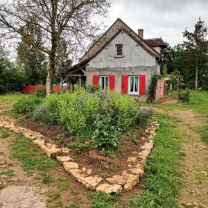 an old house with red doors and a garden at L'Orée du bois Narcy in Narcy