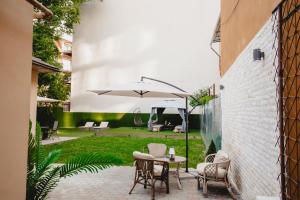 a patio with a table and chairs and an umbrella at Eden Central Boutique Suites - Garden & Spacious Apartments in Cluj-Napoca