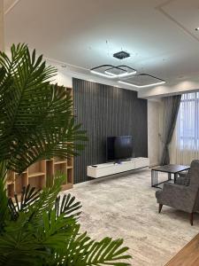 a living room with a tv and a chair and a plant at Coco Chanel Apartment in Bishkek in Bishkek