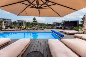 a swimming pool with an umbrella and lounge chairs at Baltic Cozy Spot in Palanga