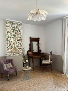 a living room with a chair and a table and a mirror at Le logis blanc bed&breakfast in Coursan