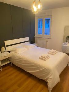 una camera da letto con un grande letto bianco con asciugamani sopra di Grand 2 pièces Eurométropole de Strasbourg proche Europa Park avec terrasse a Plobsheim