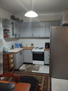 a small kitchen with white cabinets and a refrigerator at Αποστολος in Tríkala +12 photos