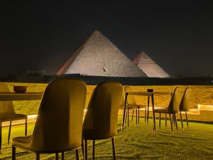 un tavolo e sedie con le piramidi sullo sfondo di Maria Pyramids House a Il Cairo