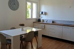 a kitchen with a table and chairs and a clock on the wall at Appart cosy proche forêt in Vert-Saint-Denis