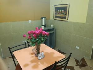 a table with a vase of pink flowers on it at Hostal Terranova Quitumbe in Quito