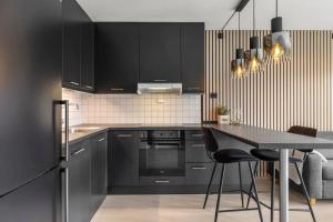 a kitchen with black cabinets and a table with chairs at Demims Apartments Lillestrøm City Centre - Parking in Lillestrøm +5 photos